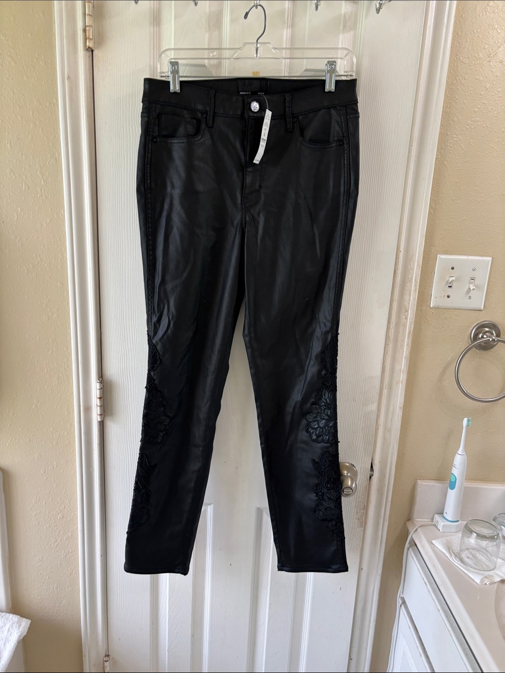 White House Black Market Black Coated Slim Jeans with flower appliqué. NWT